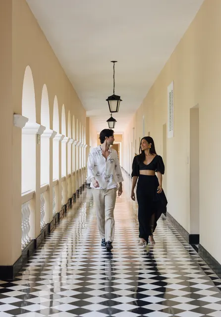Pareja en una galería con columnas y piso ajedrezado