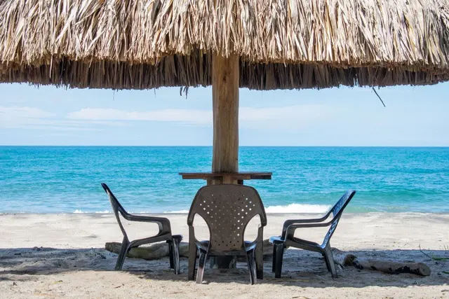 Mesa frente al mar bajo un techo de palma
